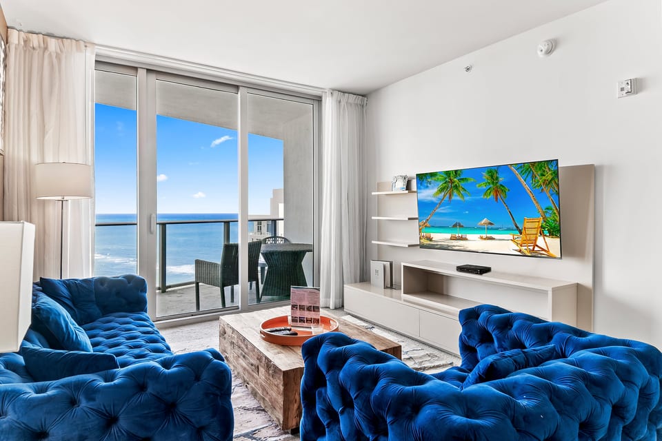 Oceanview lounge with balcony seating, luxe blue sofas, and smart TV