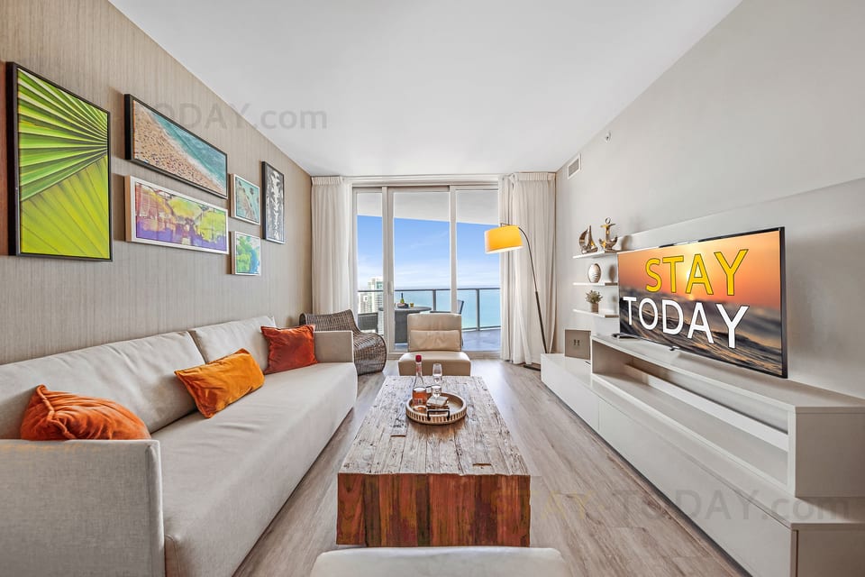 Bright ocean-view living room with balcony, big TV, and modern decor