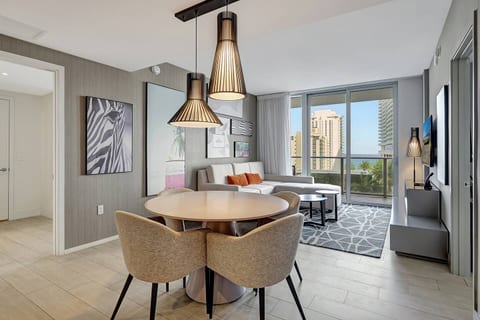 Natural light fills the space highlighting the modern furnishings and tasteful artwork. The dining area connects effortlessly to the living room, creating a bright and inviting atmosphere for meals and relaxation.
