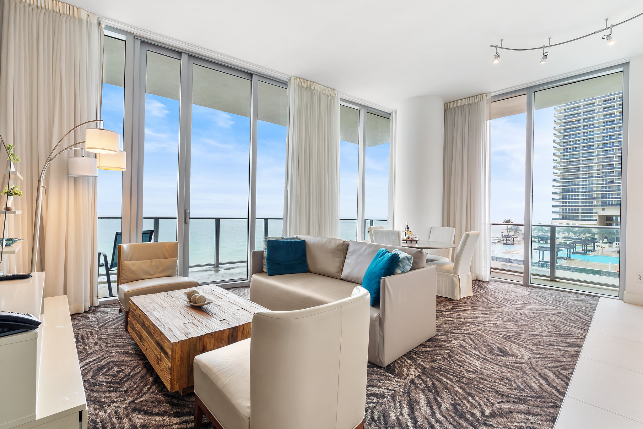 Sunny oceanfront lounge with floor-to-ceiling windows, balcony & dining nook