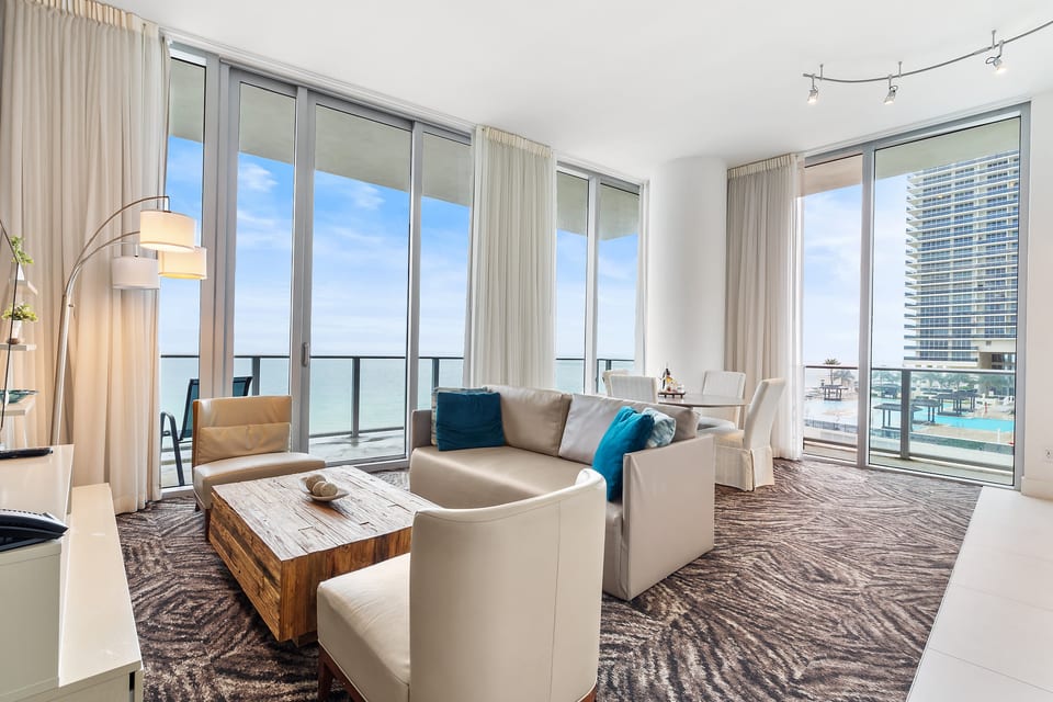 Sunny oceanfront lounge with floor-to-ceiling windows, balcony & dining nook