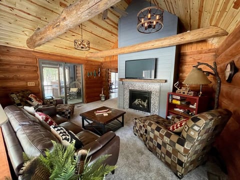 One of the rustic log cabin vaulted living room with large screen TV, Roku, gas firepalce, New furnishings and fixtures, and access to the screened porch.