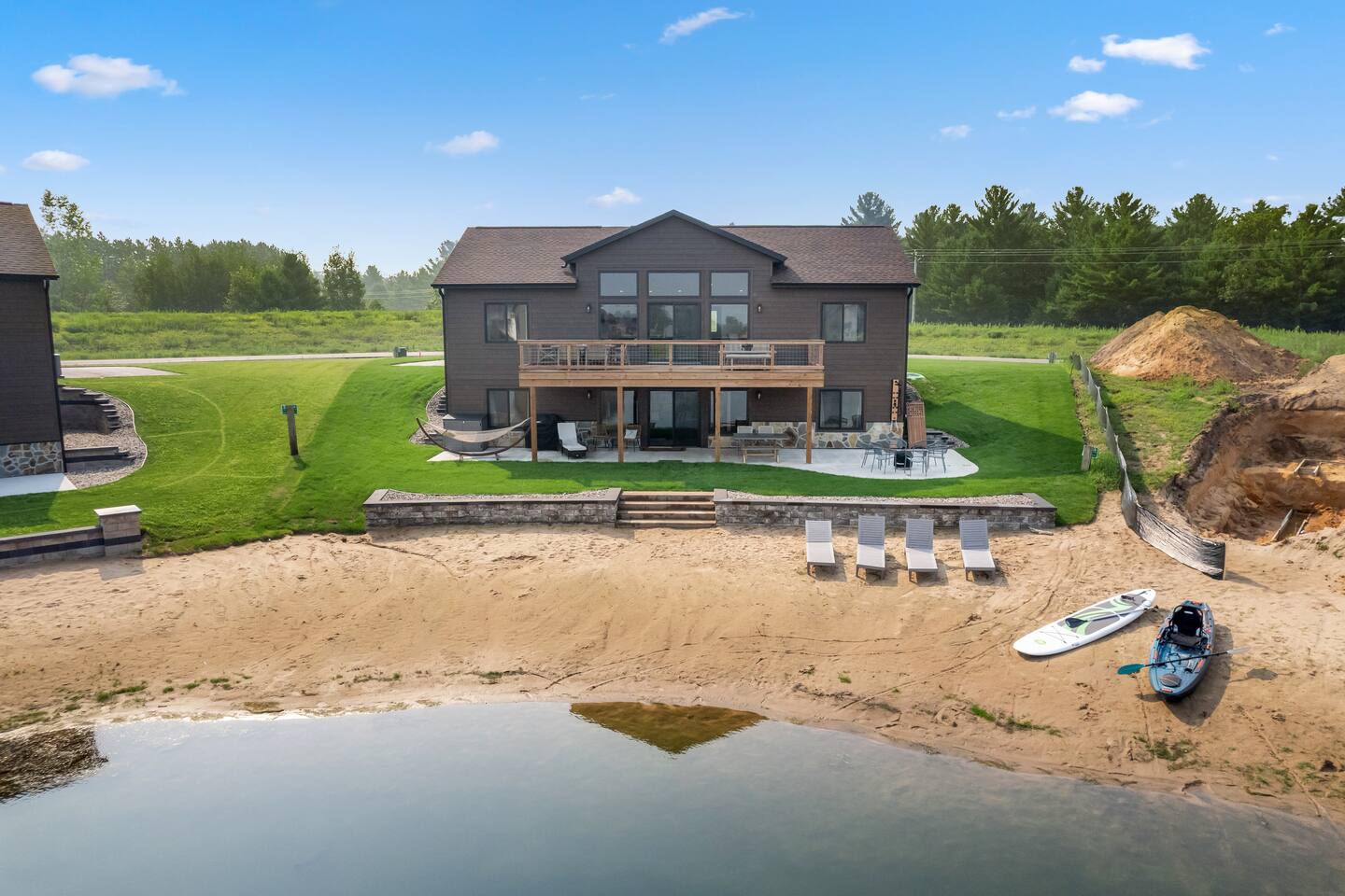 Enjoy direct lake access from the sandy beach. Backyard includes a fire pit w/chairs, poatio & deck seating, hammock, a grill (propane provided), beach chairs, kayaks & paddle boards w/life jackets, corn hole, badminton, & an outdoor shower