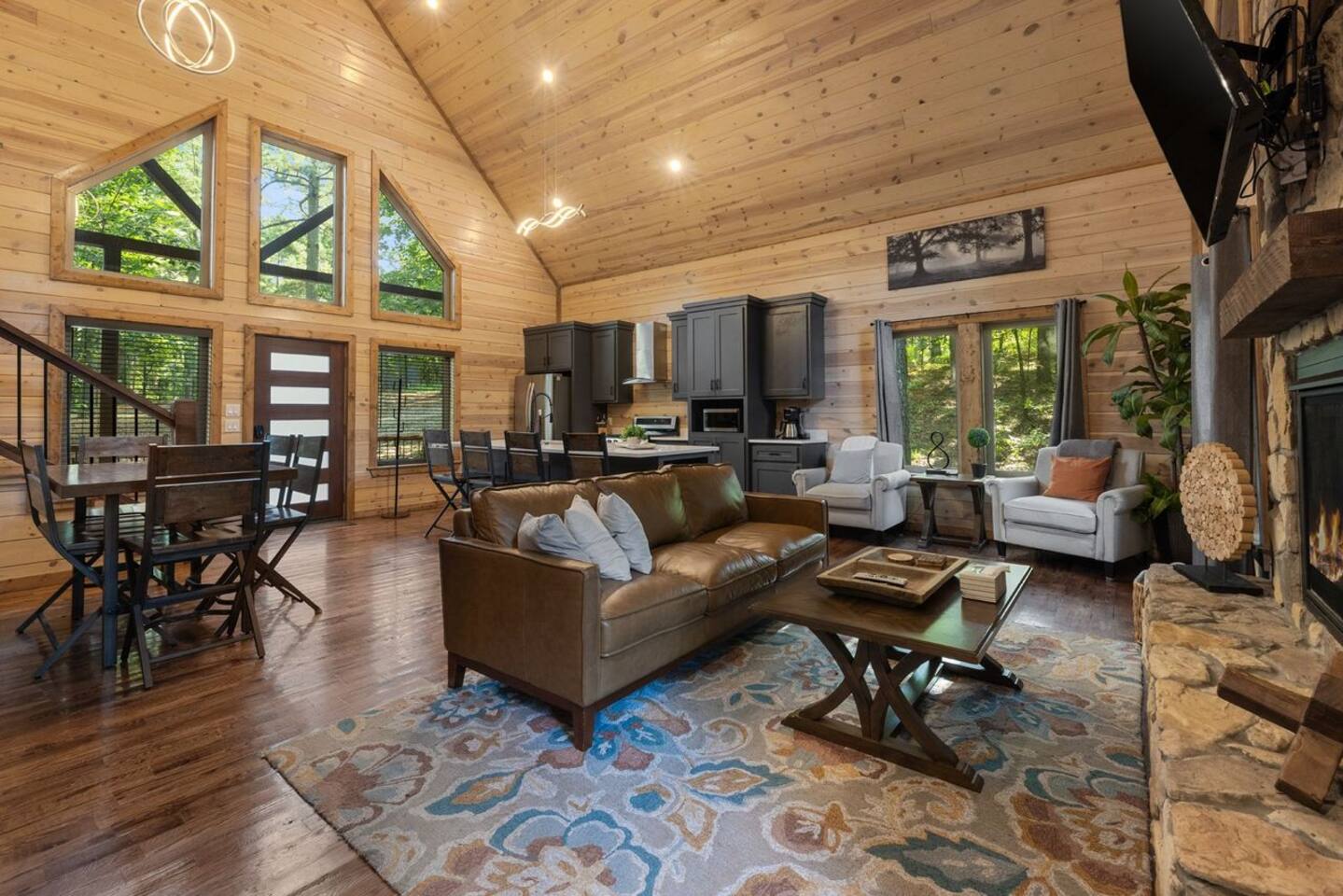 Spacious open-concept living room with high vaulted ceilings, warm wood accents, and large windows that fill the space with natural light — the perfect spot to relax and reconnect.