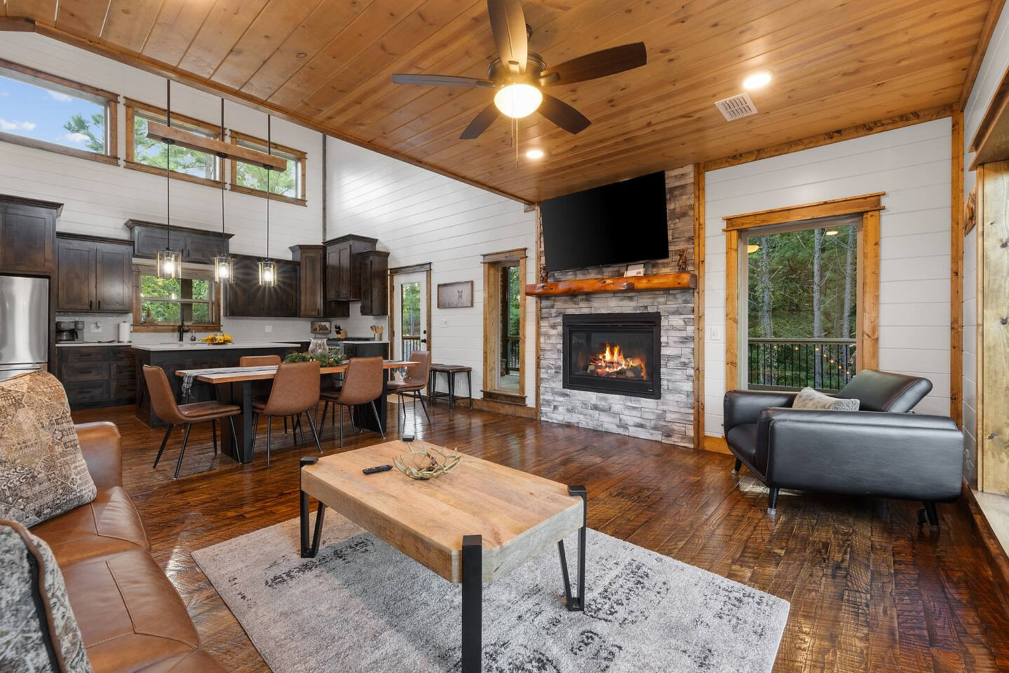 Cozy open-concept living with a warm fireplace, high ceilings, and a fully equipped modern kitchen.