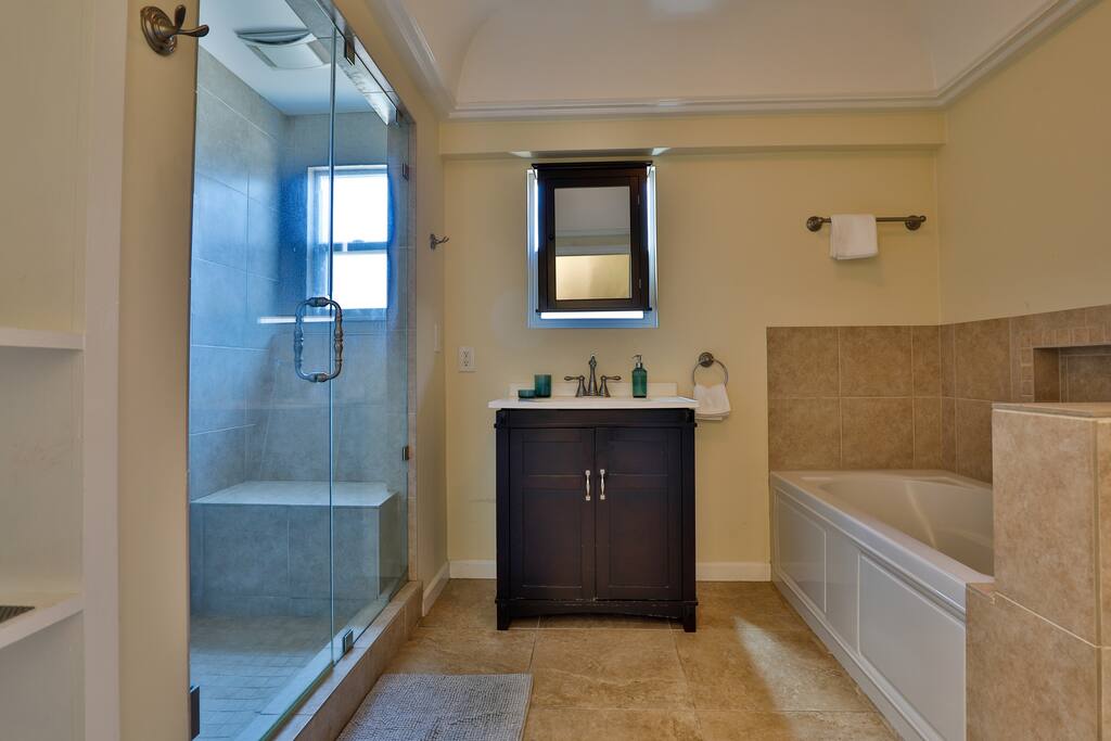 An efficient and well-lit bathroom, with a generously sized shower thoughtfully crafted to maximize guest comfort.
