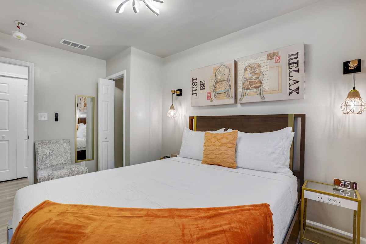 Our foxy orange queen bedroom includes two night lamps, hangers, and a side tables with extra plugs and usb ports. The bathroom is just steps outside the room.