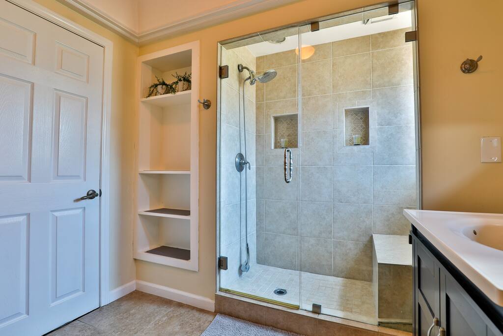 An efficient and well-lit bathroom, with a generously sized shower thoughtfully crafted to maximize guest comfort.