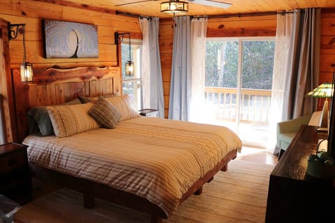 Primary Suite on 1st Floor with King sized Bed, 40" TV, huge en suite bathroom, and Sliding Glass Doors leading out to the Porch, Firepit, and Creek