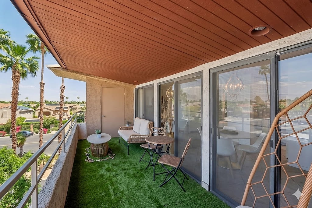 Shaded turf balcony with lounge seating and palm-lined views