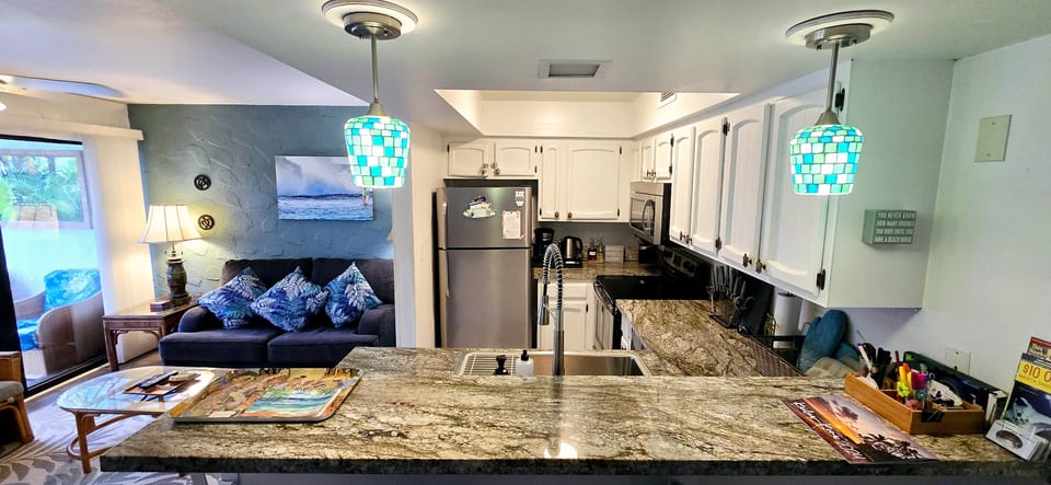 Welcome to your home away from home at the Aloha Lani condo #A208. This panorama view shows you the kitchen and living room with our newly updated flooring and granite counters. 