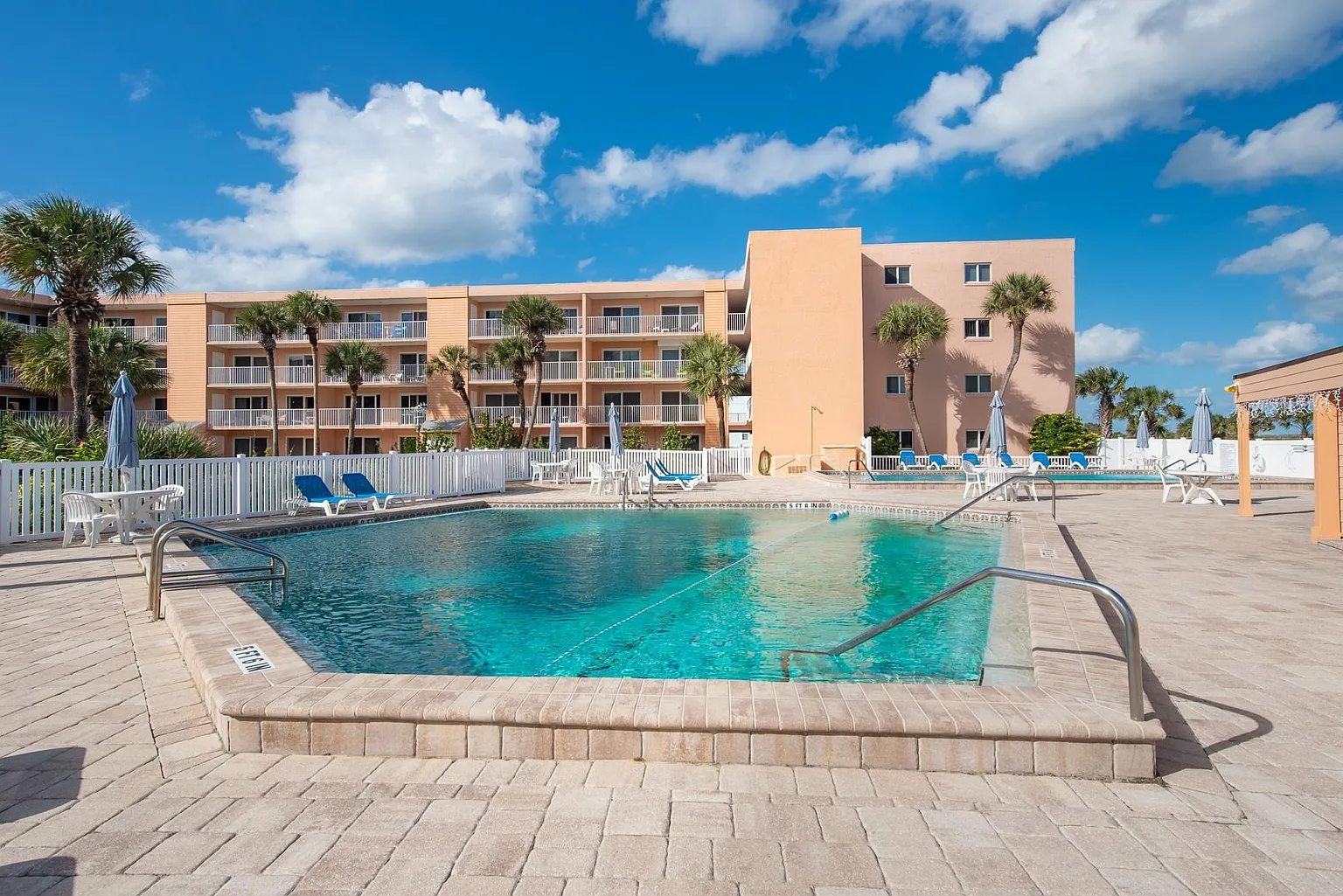 Second community pool with lounge chairs, palm trees, and plenty of space to relax under the Florida sun.