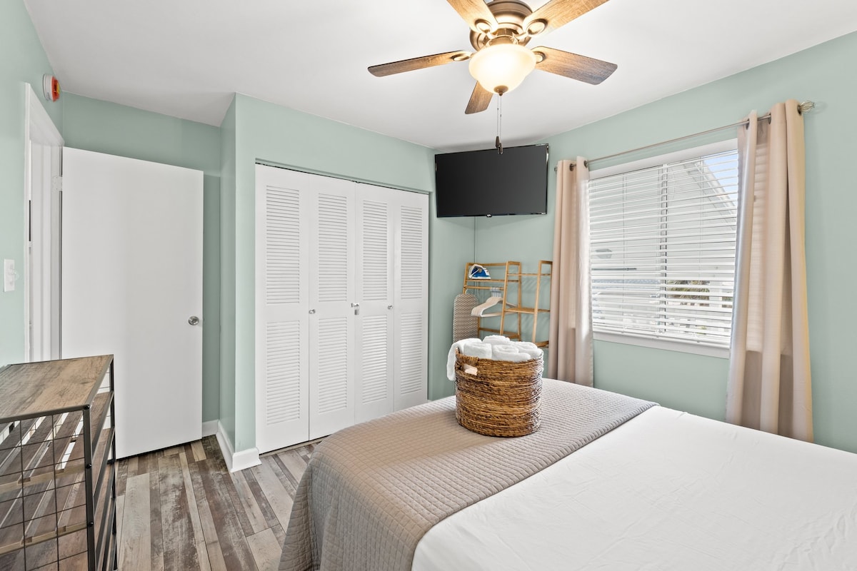 Spacious bedroom with double closet, TV, and window views for a restful stay.