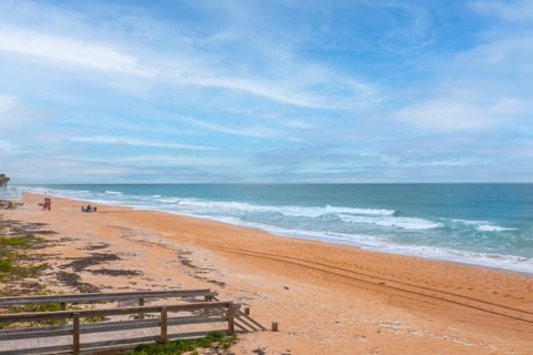 Steps to the coral colored sand and ocean. Lifeguard stand is only a few yards away.