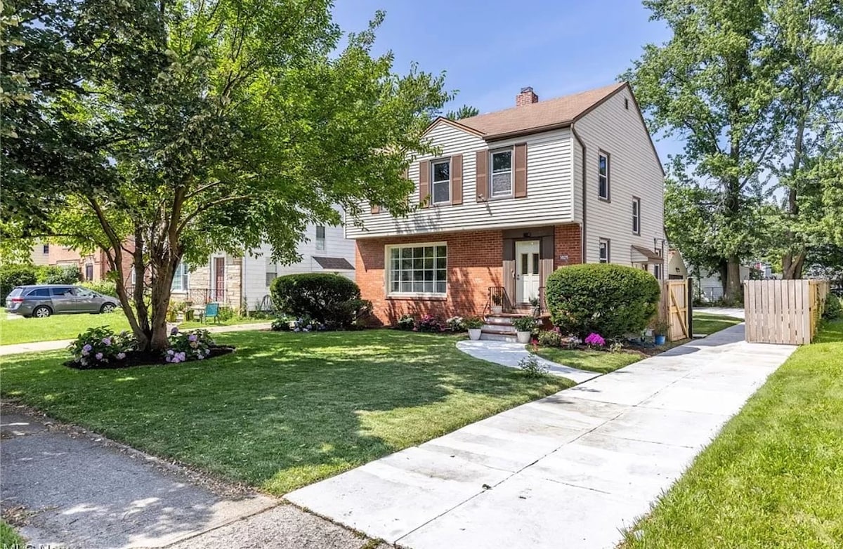 This is a charming two-story, family home with a classic suburban style. It has a well-maintained appearance and a welcoming front yard.