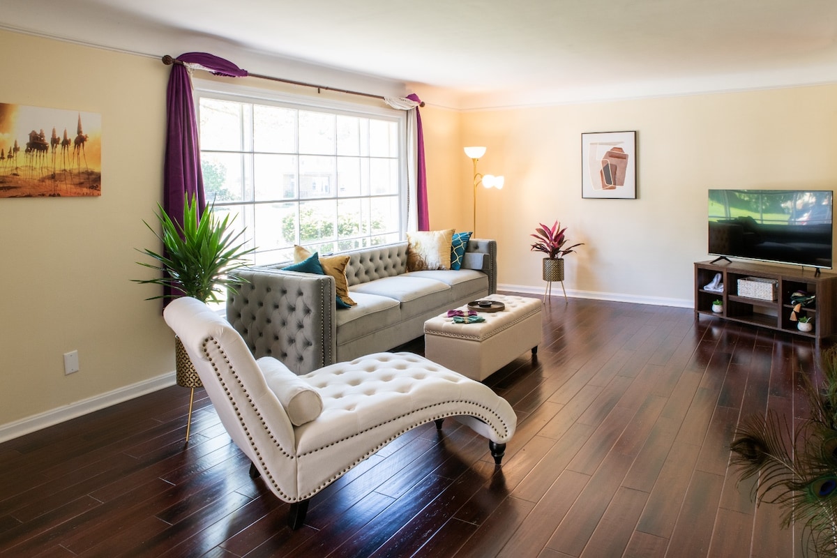 living room that seamlessly blends modern sophistication with eclectic charm. The inviting grey sofa is perfect for lounging, while the sleek TV invites cozy movie nights. With carefully curated decor and textures.