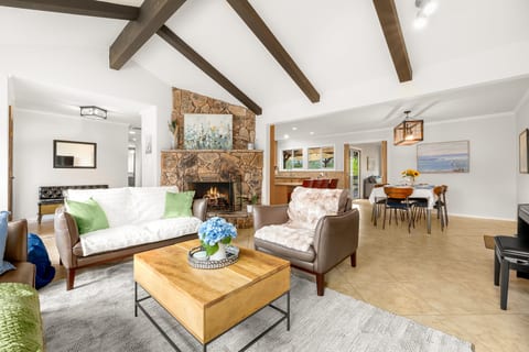 Bright great room with vaulted beams, stone fireplace, and open dining area