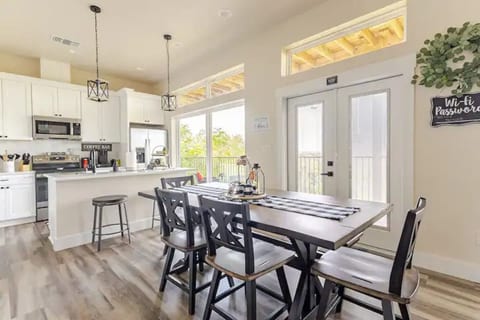 Dine in style at this chic table, flowing into a bright white kitchen with stainless steel appliances and a cozy rustic touch. Perfect for meals & mingling!