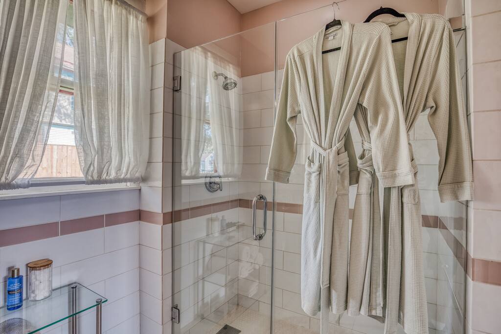 Fully redone bathroom with glass shower.  Beautiful designer wallpaper finishes off this bathroom that has a fun, retro vibe. Fresh robes for you to feel comfortable in every way.