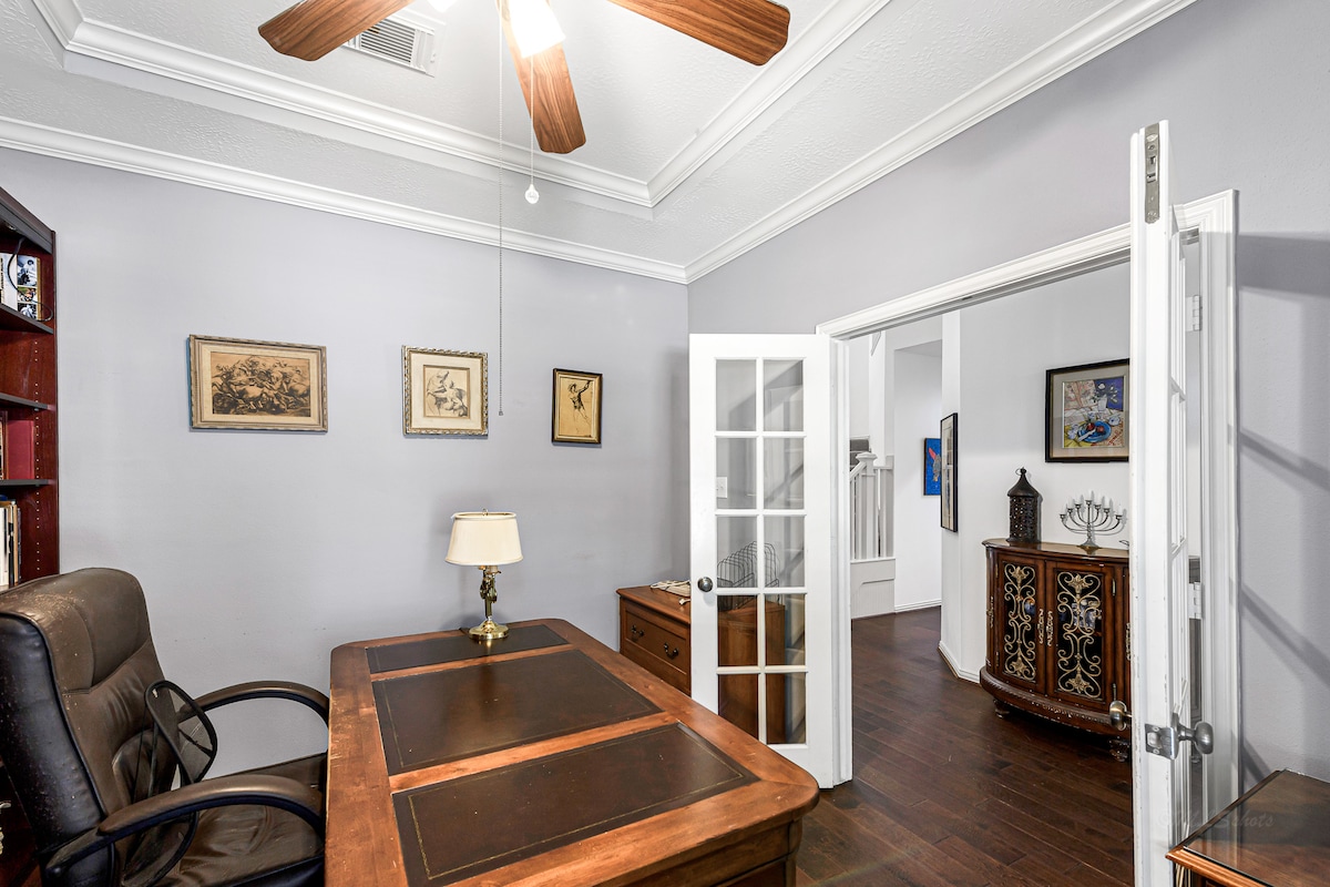 Spacious desk and library shelves create a professional, focused setting.