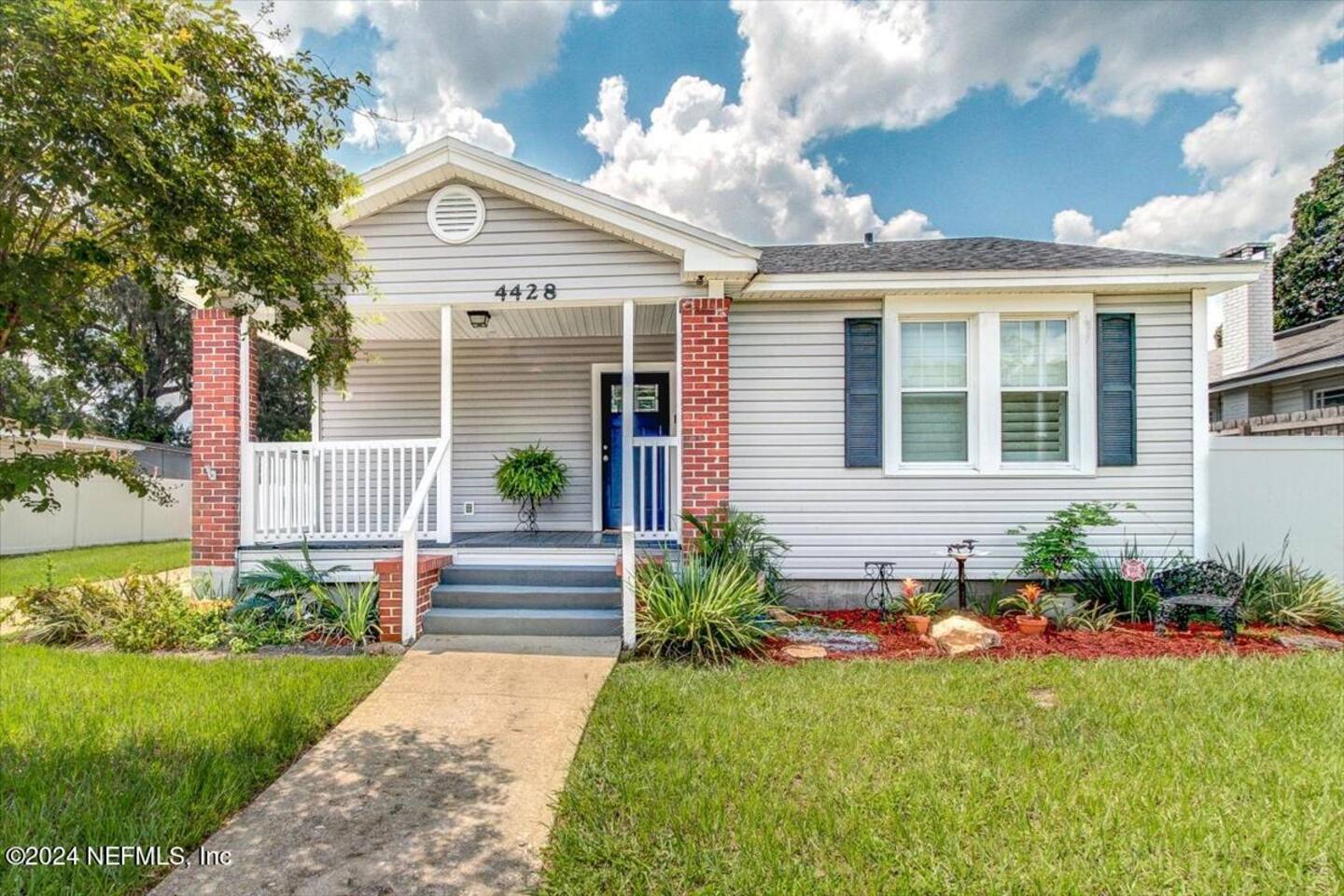 Charming and freshly updated home exterior with a classic front porch, brick accents, and a bright blue door. A warm and inviting welcome from the moment you arrive
