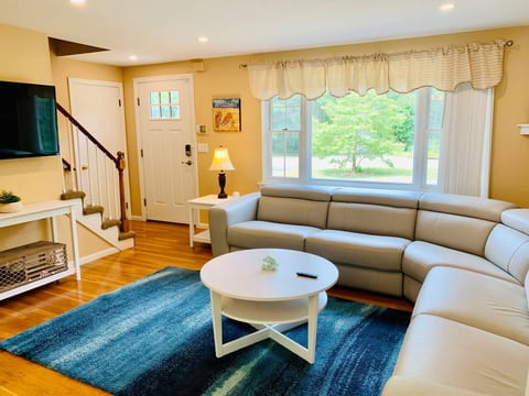 Bright and spacious living room with plush seating and natural light, perfect for relaxing, family gatherings, or cozy nights during your Cape Cod getaway.