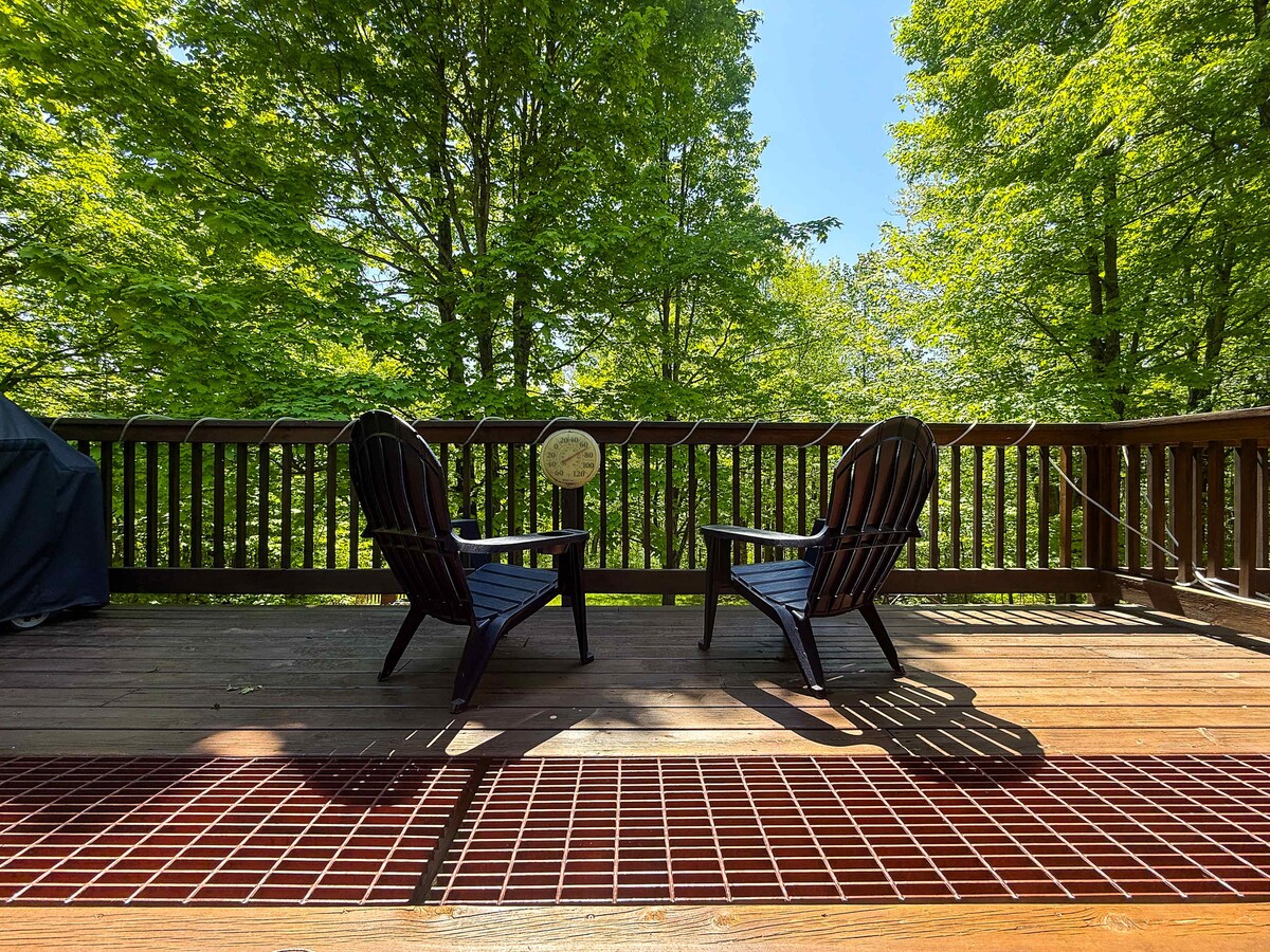 Spacious Back Deck at Cabin Fevers U.P. | Enjoy peaceful mornings or sunset evenings surrounded by the Northwoods. This deck features outdoor seating, a grill, and forest views — perfect for relaxing after exploring Big Powderhorn Mountain or Lake Superior.