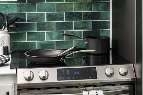 Cook with ease using a clean electric range and quality cookware — framed by a bold green backsplash that adds a pop of color.