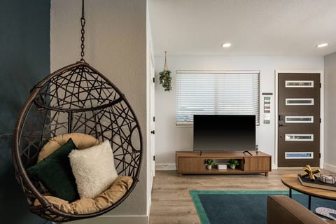 The living space is anchored by a unique egg chair and relaxed layout, perfect for lounging or movie nights.