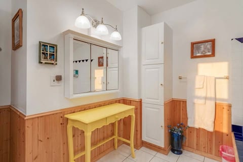 Bright bathroom with charming yellow accent table and ample storage