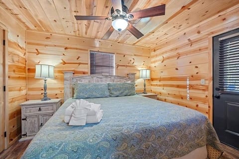 Warm, inviting bedroom with wood paneling, soft bedding, and peaceful forest charm. Enjoy restful nights and cabin comfort in a serene, cozy atmosphere.