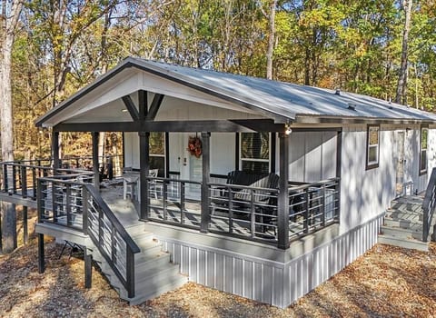 Modern cabin with a stylish covered porch and forest views. Enjoy peaceful mornings, cozy evenings, and a relaxing outdoor space perfect for unwinding.