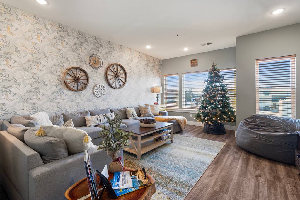 Bright and inviting living room featuring a spacious sectional sofa, stylish wall décor, and large windows that fill the space with natural light.