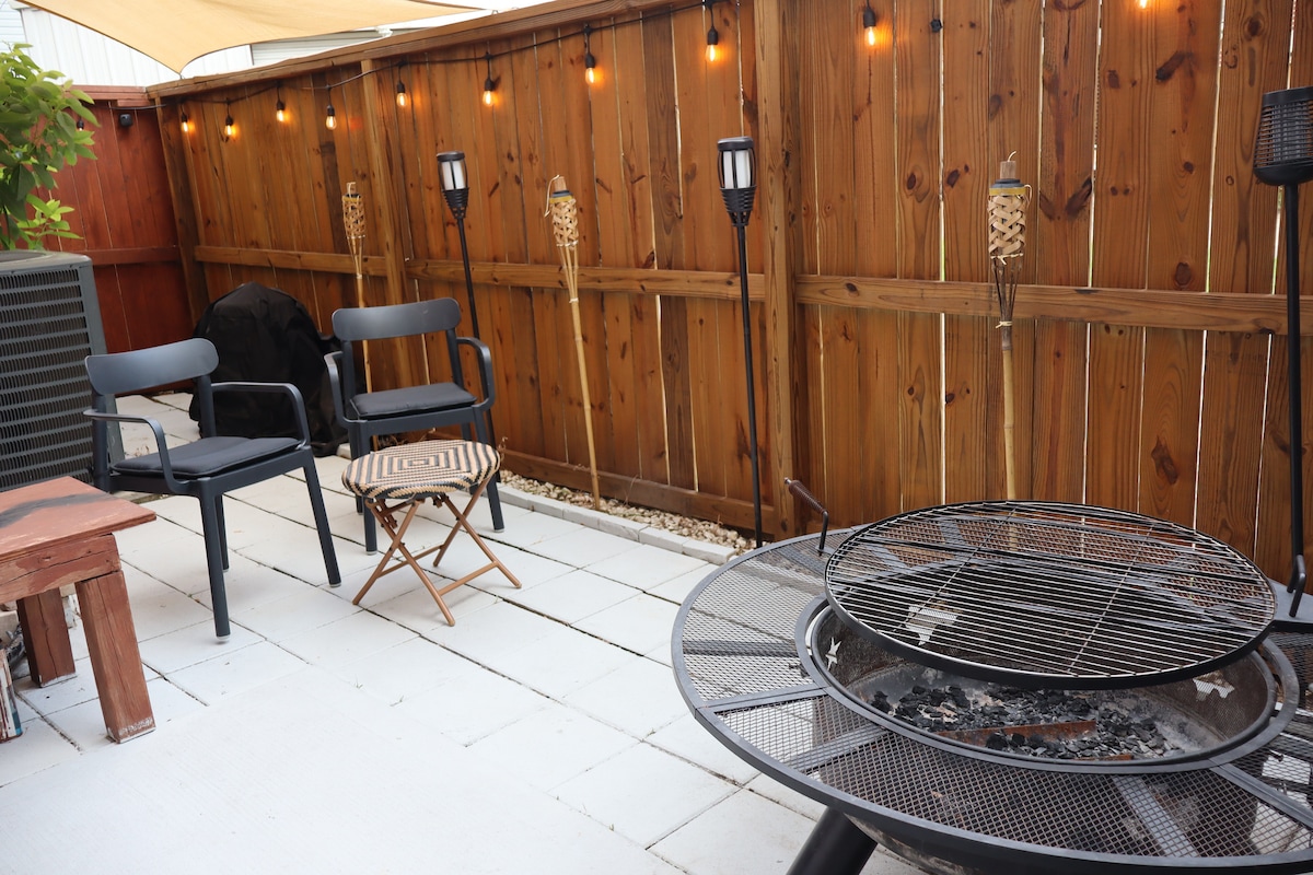 Comfortable outdoor patio equipped with a firepitt, BBQ grill and string lights!