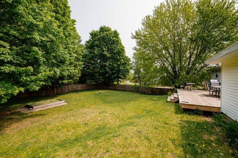 Large deck with grill and patio set overlook the fully fenced yard.