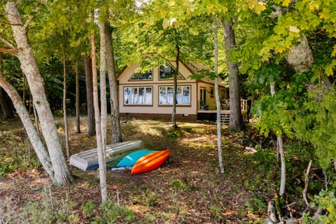 Cottage nestled among trees with kayaks ready for use