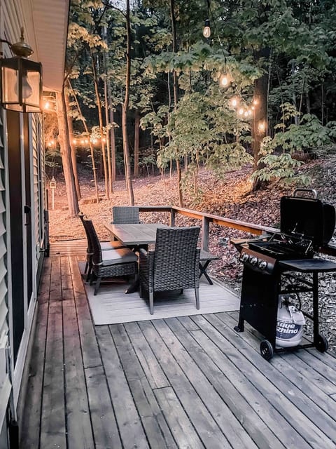 The back deck faces the forest and offers outdoor dining, a gas grill, and cozy string bulbs to set the evening mood.