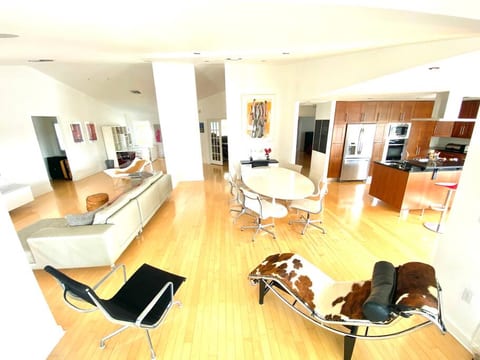 Living and dining room with marble Saarinen table, Eames chairs, Federicia Stingray chair, leather sofa and a Le Corbusier pony chaise lounger.