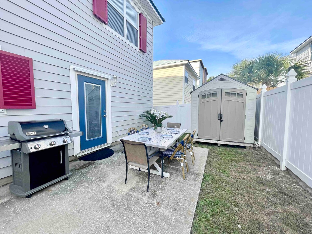 Fenced in backyard with Weber grill, dining table and storage shed.