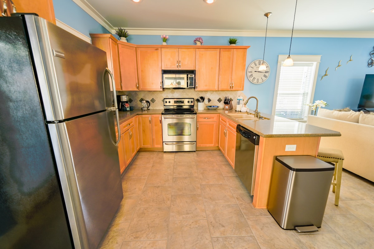 Fully stocked gourmet kitchen with stainless steel appliances.