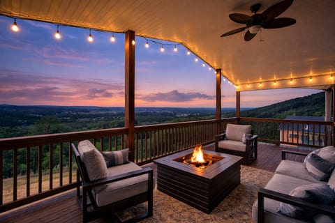 Covered deck with fire pit, string lights, and sweeping sunset views
