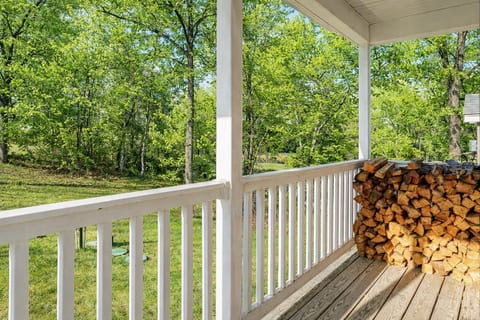 Covered porch with forest views and stacked firewood—peaceful retreat