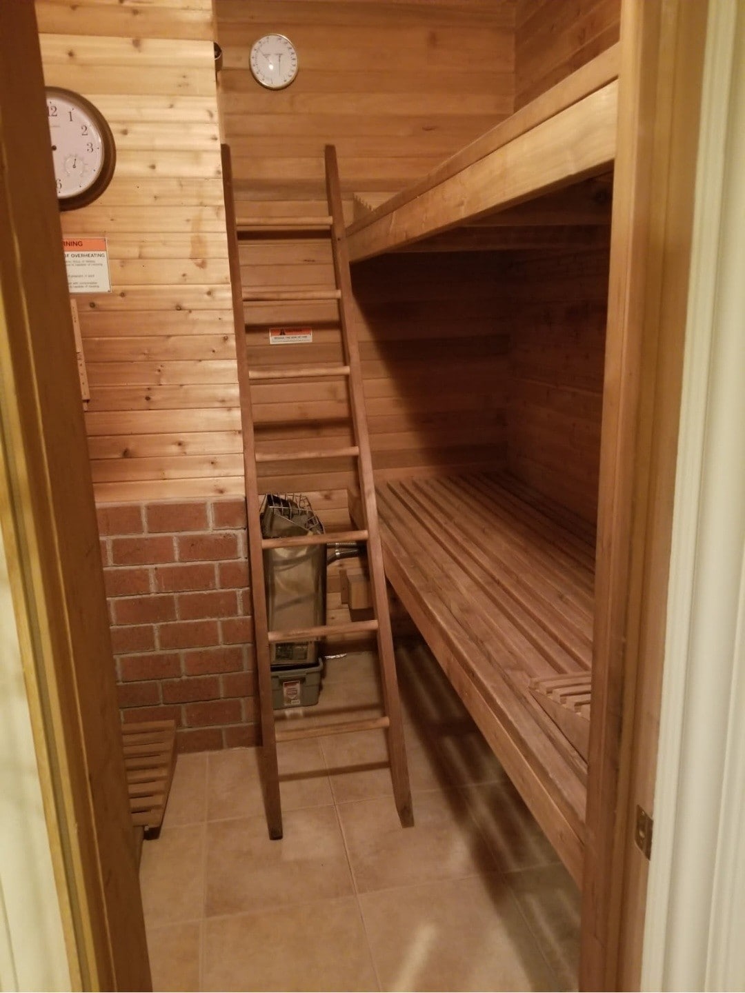 Private cedar sauna with tiered seating, brick accents, and warm wood finishes.