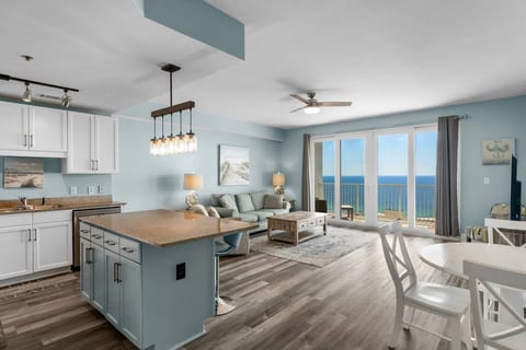 Bright open-concept kitchen and living space with a large island, cozy seating, and breathtaking Gulf views right from the balcony doors.
