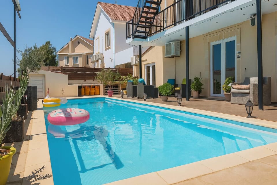 Long 4 × 10 m outdoor pool extending alongside the villa, with sun loungers, umbrellas and views towards the surrounding landscape.