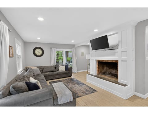Bright lounge with fireplace, big sofas, smart TV, and patio access