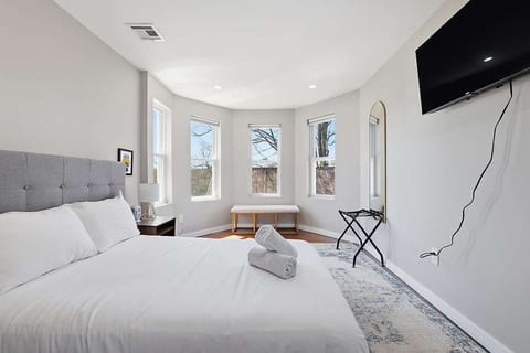 Sunny bedroom with bay windows, bench seating, plush bed & smart TV