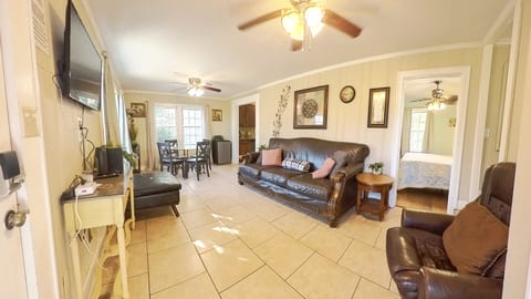 Bright open living room with dining area, TV, and cozy leather seating