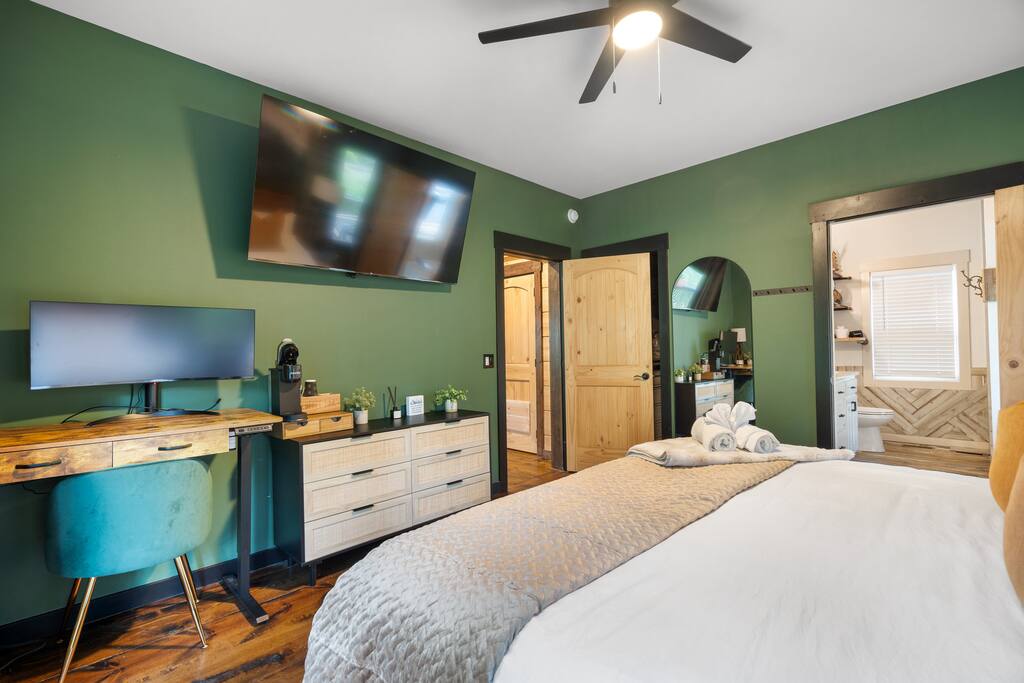 Electric standing desk, and large wide monitor easily connected to your laptop (has HDMI cord) for your convenience or use as a make-up vanity. You’ll be super comfy with the paired green velvet chair. 
Also, your own complete Keurig setup. 