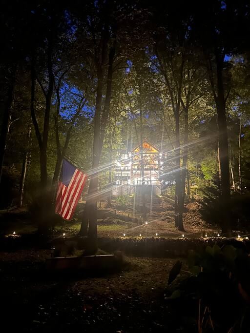 The backyard stretches wide—this view from the river and fire pit area shows just a portion of the full backyard space. Enjoy plenty of room and the elevated view of the cabin perched above.